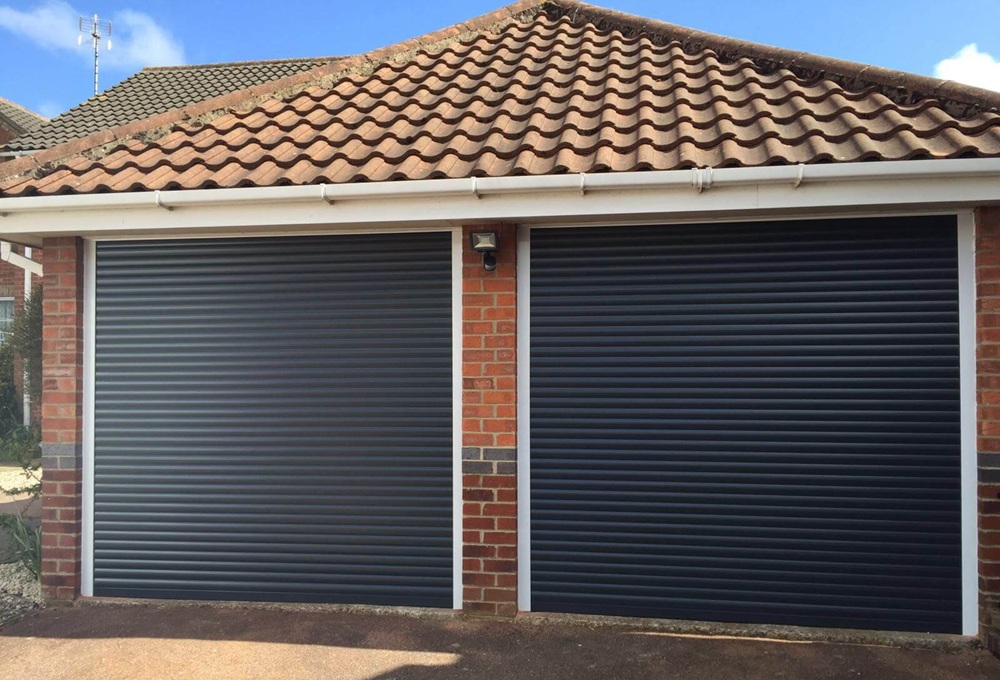 A pair of black roller garage doors installed on a detached brick garage, offering security and insulation.