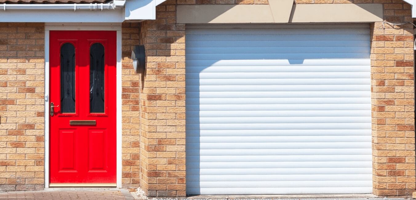 A white roller garage door next to a bold red front door on a modern brick home, illustrating security and style.